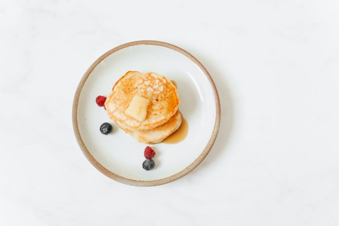 pancakes with red and black berries on white ceramic plate
